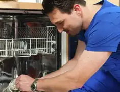 Dishwasher repair technician inspecting and servicing an open dishwasher in Ogden, UT