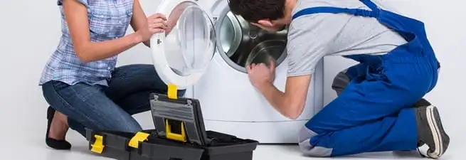 Washer repair technician inspecting a front-load washing machine with tools in Ogden, UT