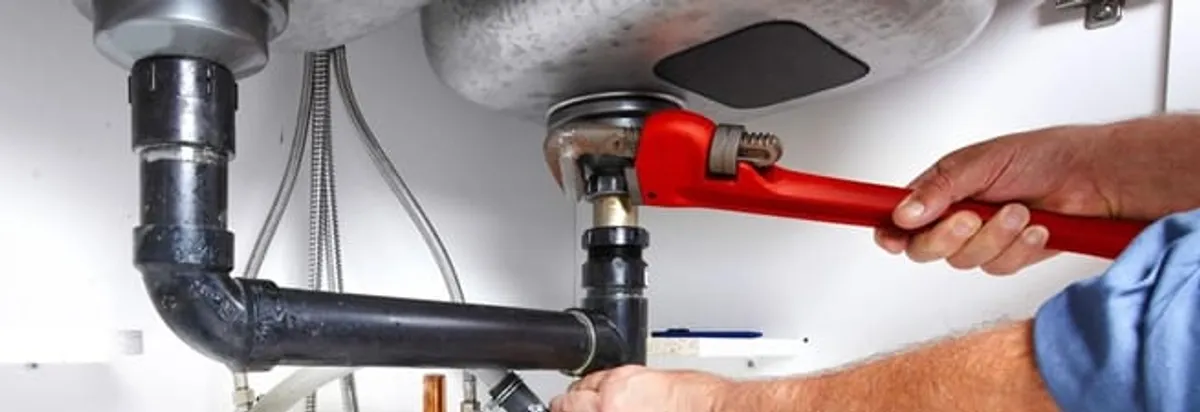 Garbage disposal repair technician tightening the sink drain and disposal connection in Ogden, UT