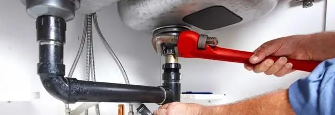 Garbage disposal repair technician tightening the sink drain and disposal connection in Ogden, UT