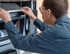 Appliance repair technician replacing a microwave vent filter in Ogden, UT