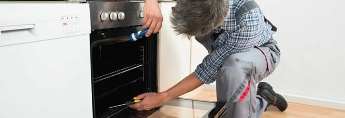 Oven repair technician inspecting and servicing an electric oven in Ogden, UT