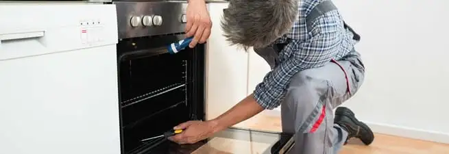 Oven repair technician inspecting and servicing an electric oven in Ogden, UT