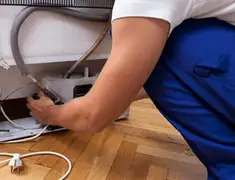 Appliance repair technician fixing refrigerator water line and connections in Ogden, UT