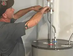 Water heater repair technician tightening supply line connections in Ogden, UT