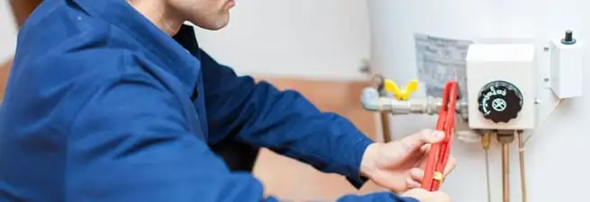 Water heater repair technician adjusting the temperature control and gas valve in Ogden, UT